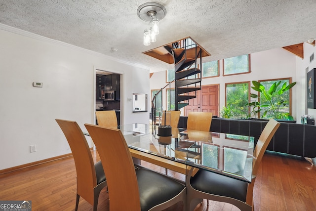 dining area with a textured ceiling, crown molding, and hardwood / wood-style flooring