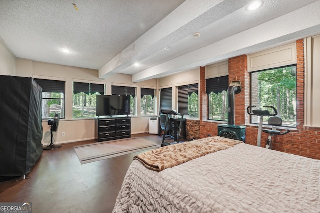 bedroom with a textured ceiling, beam ceiling, and a wood stove