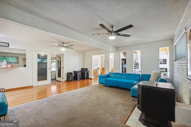 living room featuring ceiling fan, a textured ceiling, light wood-type flooring, and a wood stove