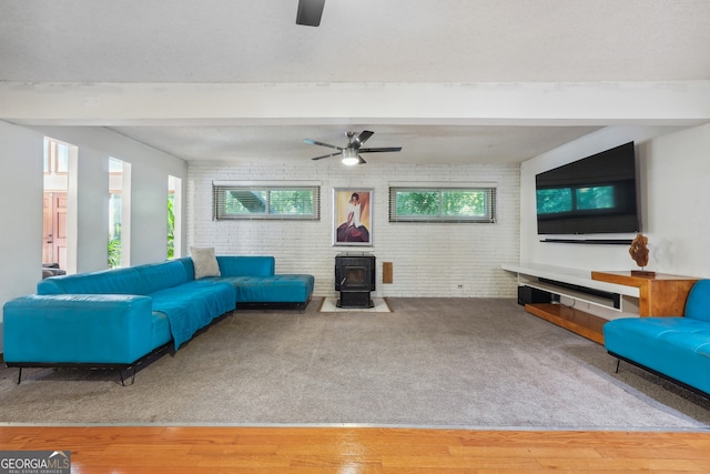 living room with a wealth of natural light, hardwood / wood-style floors, a wood stove, and brick wall