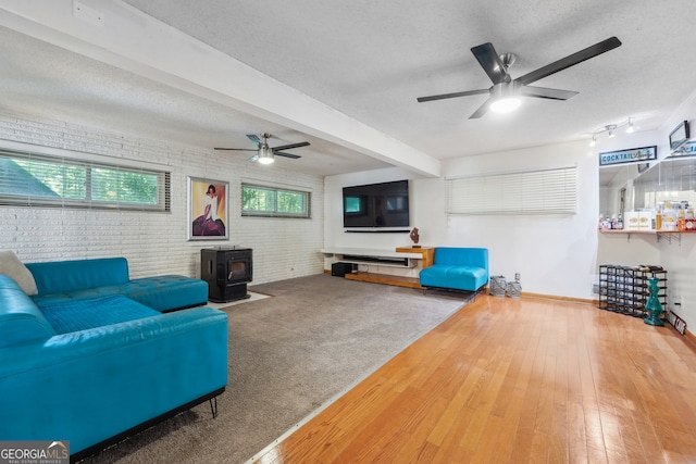 living room with brick wall, hardwood / wood-style floors, a wood stove, and a wealth of natural light