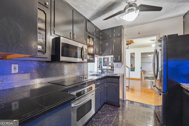 kitchen featuring dark wood-type flooring, backsplash, stainless steel appliances, a textured ceiling, and ceiling fan