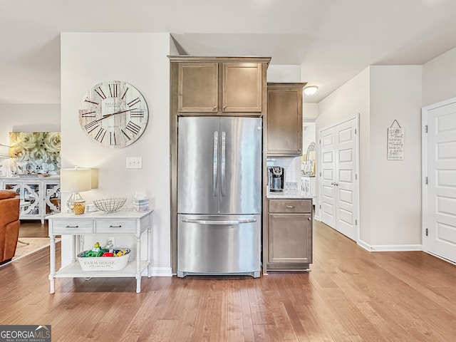 kitchen featuring hardwood / wood-style floors, stainless steel fridge, and tasteful backsplash