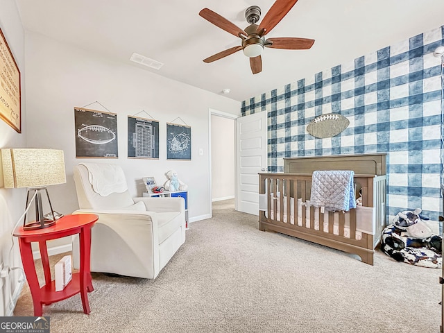 carpeted bedroom with ceiling fan, a fireplace, and a nursery area