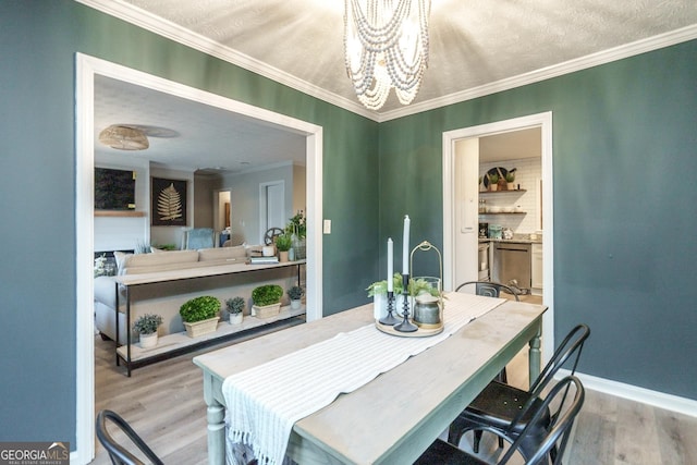 dining area featuring a textured ceiling, ornamental molding, an inviting chandelier, and light hardwood / wood-style floors