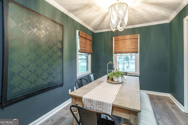 dining space with crown molding, a textured ceiling, wood-type flooring, and a notable chandelier