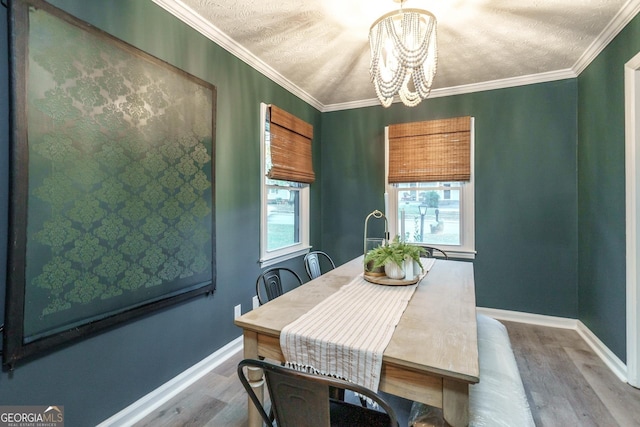 dining room with baseboards, ornamental molding, a notable chandelier, and wood finished floors