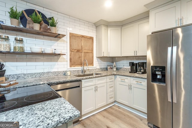 kitchen featuring sink, light stone countertops, appliances with stainless steel finishes, and decorative backsplash