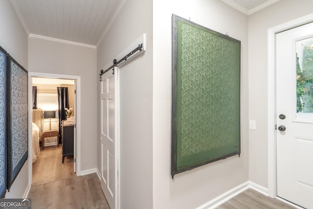 corridor with crown molding, hardwood / wood-style floors, and a barn door