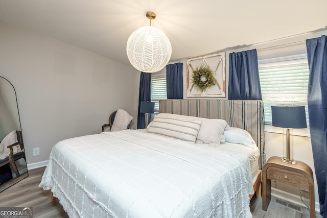 bedroom featuring visible vents, baseboards, and wood finished floors