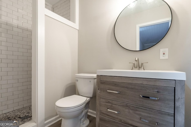 bathroom with tiled shower, vanity, and toilet