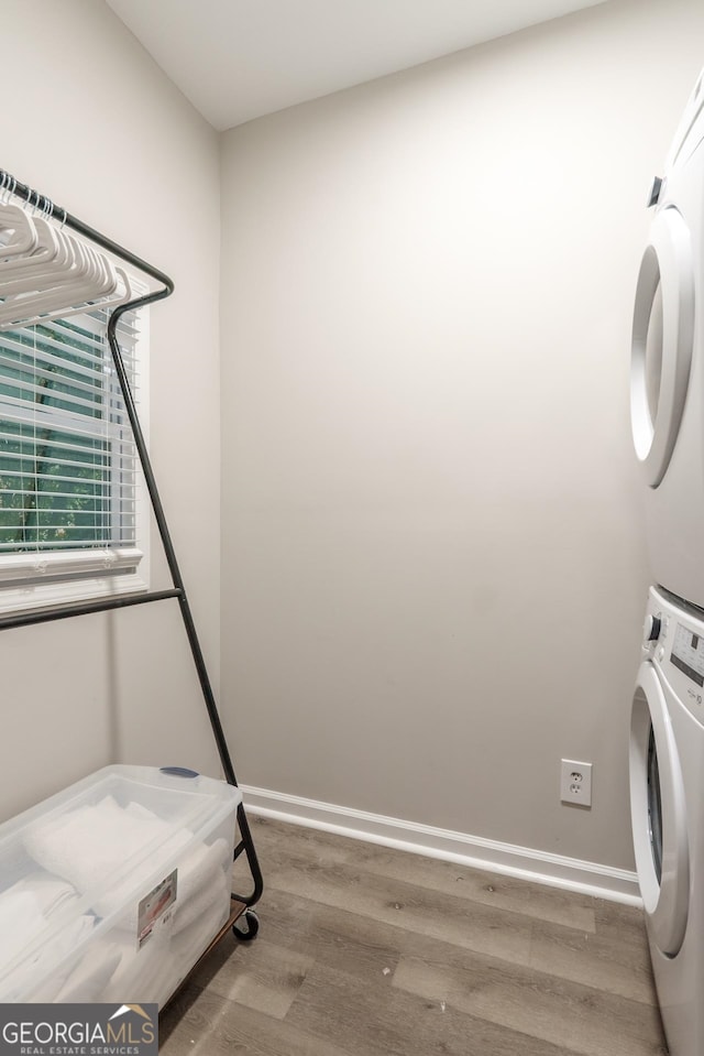 laundry room featuring wood-type flooring and stacked washing maching and dryer