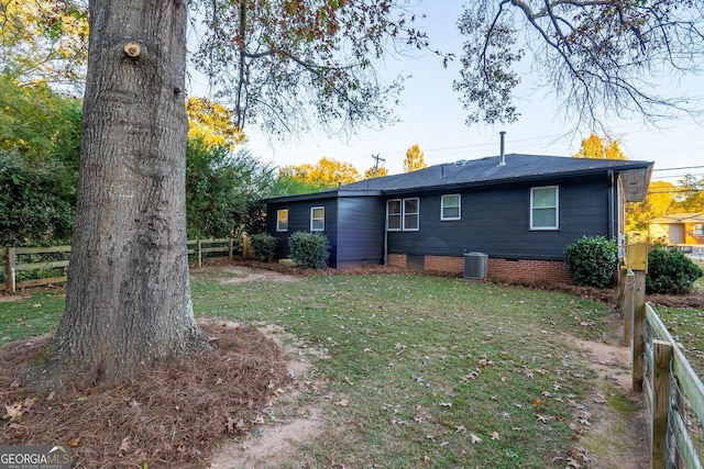 back of house with central AC, fence, and a lawn