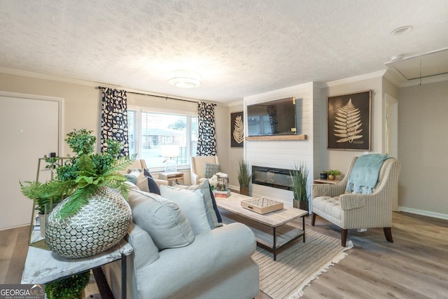 living room featuring crown molding, a textured ceiling, hardwood / wood-style floors, and a large fireplace