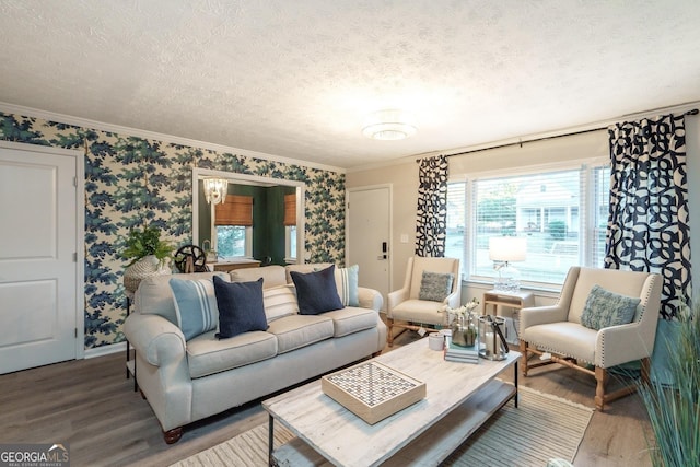 living area with wallpapered walls, crown molding, a textured ceiling, and wood finished floors