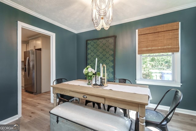 dining room featuring a chandelier, light hardwood / wood-style floors, crown molding, and a textured ceiling