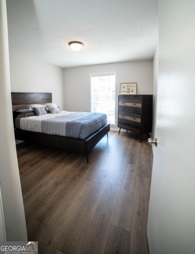 bedroom with a textured ceiling and dark hardwood / wood-style flooring