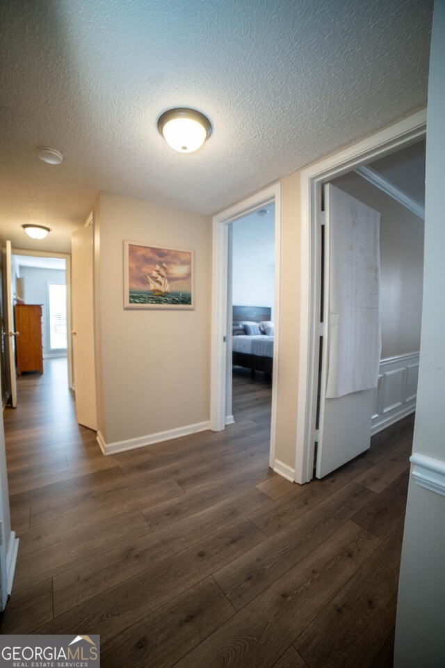 corridor with a textured ceiling and dark hardwood / wood-style floors