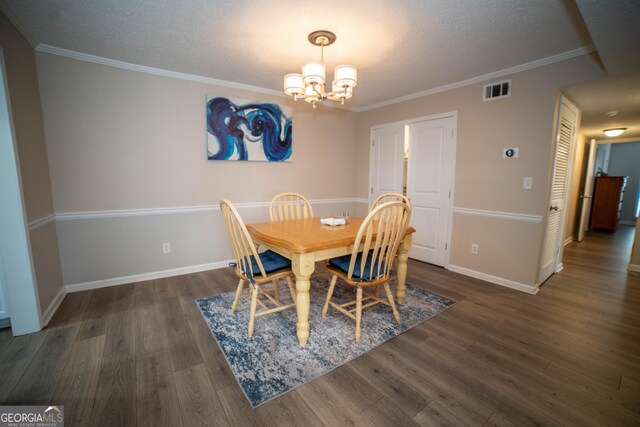 dining room with an inviting chandelier, a textured ceiling, crown molding, and dark hardwood / wood-style flooring