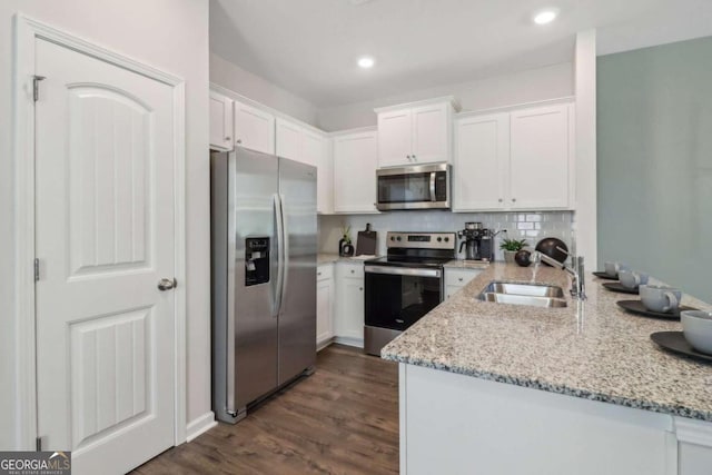 kitchen featuring white cabinetry, stainless steel appliances, light stone counters, and dark hardwood / wood-style flooring