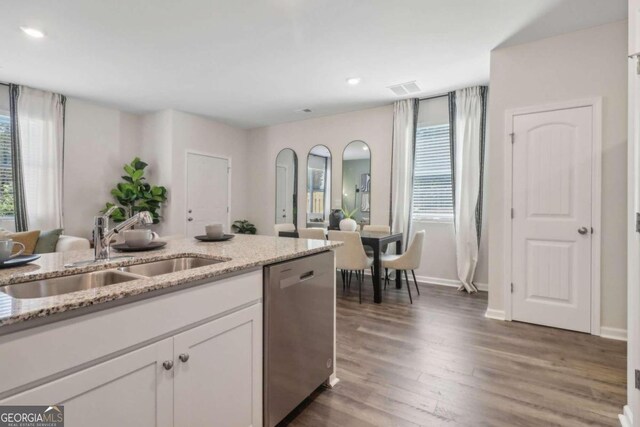 kitchen featuring light stone counters, white cabinets, sink, stainless steel dishwasher, and dark hardwood / wood-style floors