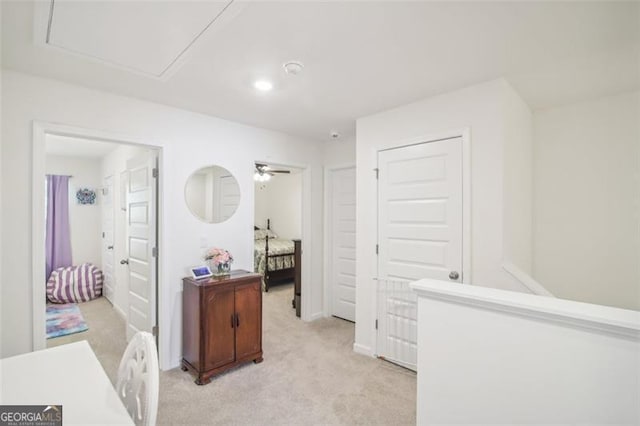 hallway with attic access and light colored carpet