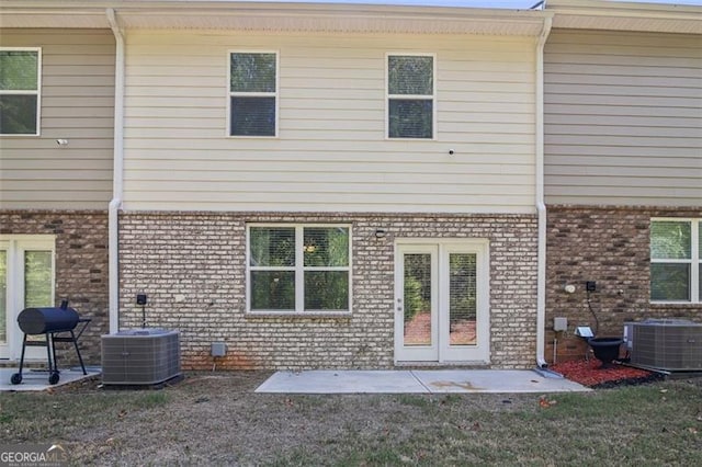 rear view of property featuring cooling unit, a patio area, and brick siding