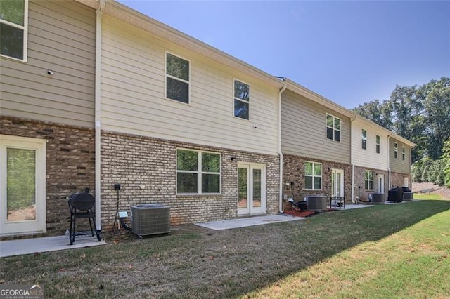 back of property with brick siding, a yard, and central air condition unit