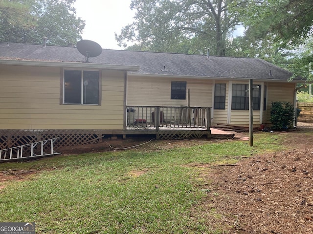 back of property featuring a wooden deck and a yard