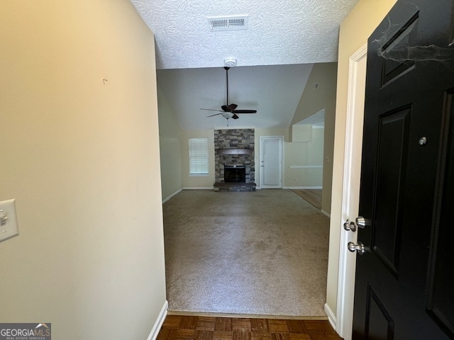 corridor with lofted ceiling, carpet flooring, and a textured ceiling