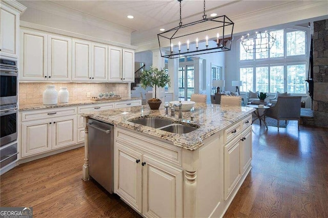 kitchen featuring crown molding, light stone countertops, sink, dark wood-type flooring, and a center island with sink