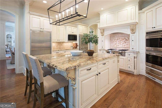 kitchen featuring crown molding, a kitchen island, dark hardwood / wood-style floors, and built in appliances