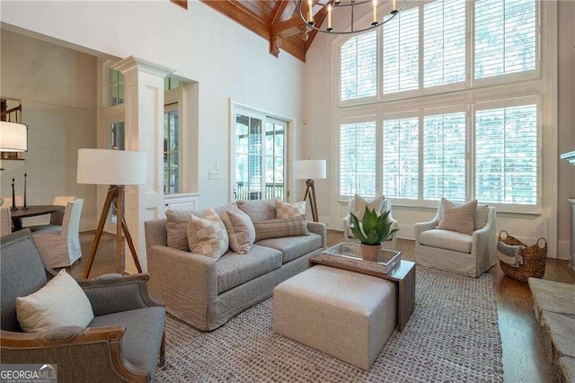 living room featuring a towering ceiling, wood-type flooring, beamed ceiling, and a healthy amount of sunlight