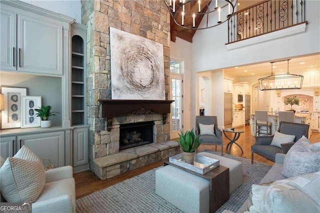 living room with a fireplace, hardwood / wood-style flooring, high vaulted ceiling, and a chandelier