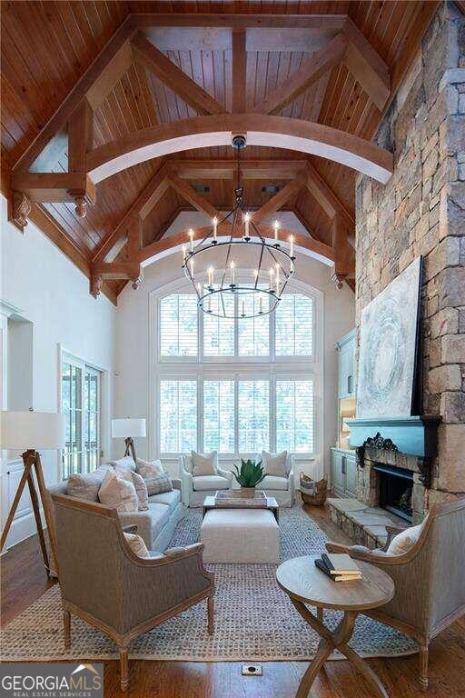 living room featuring a fireplace, hardwood / wood-style floors, a notable chandelier, high vaulted ceiling, and beam ceiling