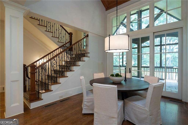 dining room with a towering ceiling and dark wood-type flooring