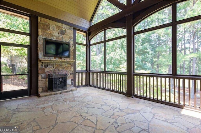 unfurnished sunroom with a fireplace, vaulted ceiling, plenty of natural light, and wood ceiling