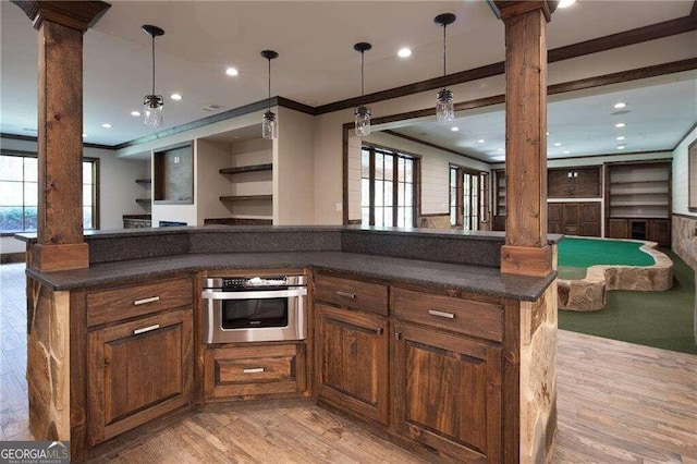 kitchen featuring plenty of natural light, ornamental molding, stainless steel oven, and ornate columns