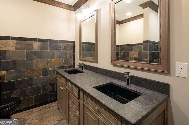 bathroom featuring vanity, wood-type flooring, crown molding, toilet, and tile walls