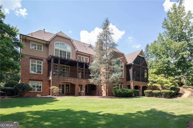 rear view of property featuring a balcony and a lawn