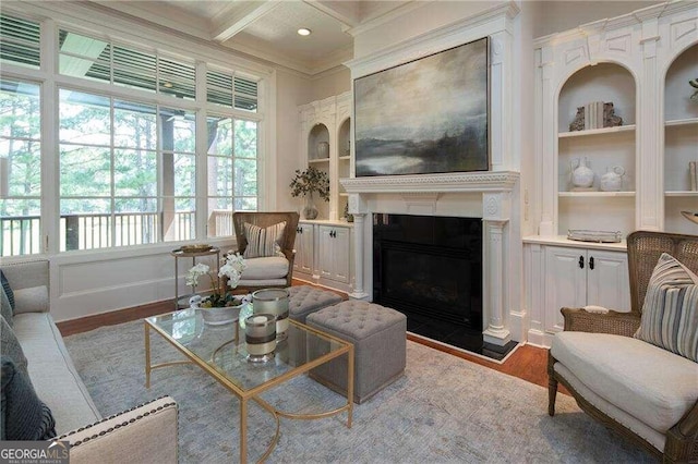 living room featuring coffered ceiling, beamed ceiling, built in shelves, crown molding, and wood-type flooring