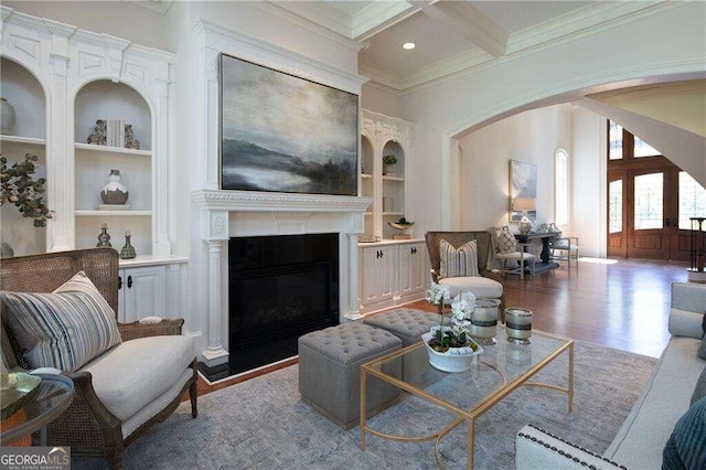 living room with coffered ceiling, crown molding, built in features, hardwood / wood-style flooring, and beam ceiling