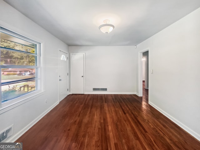 unfurnished room featuring a wealth of natural light and dark wood-type flooring