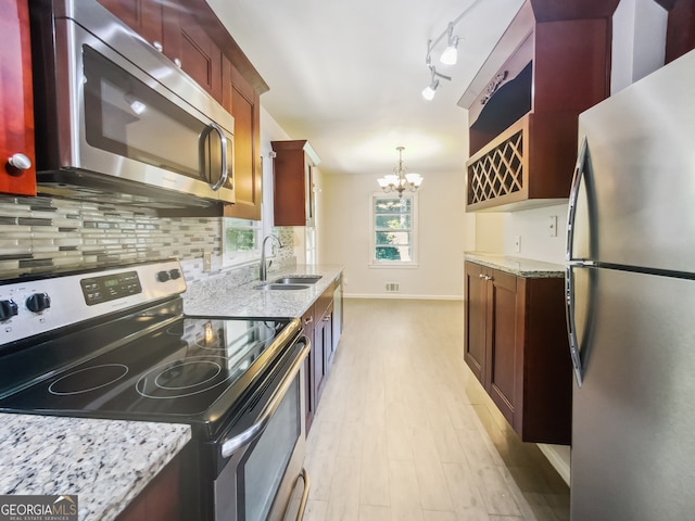 kitchen featuring light stone countertops, light hardwood / wood-style flooring, stainless steel appliances, sink, and a chandelier