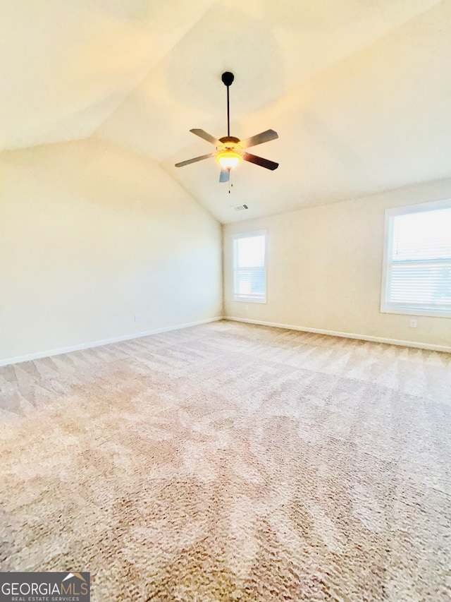 spare room featuring lofted ceiling, carpet flooring, and plenty of natural light