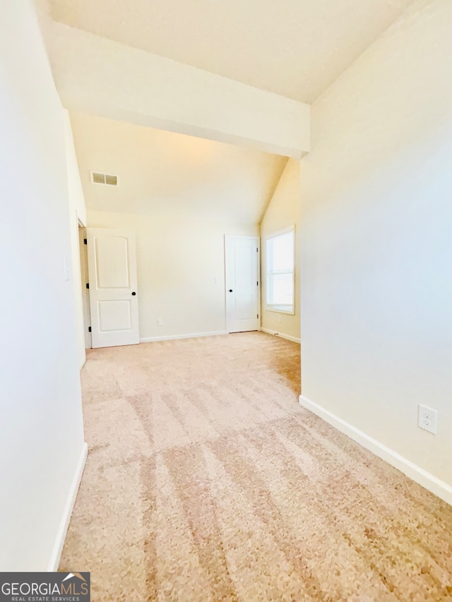 spare room featuring lofted ceiling and light colored carpet