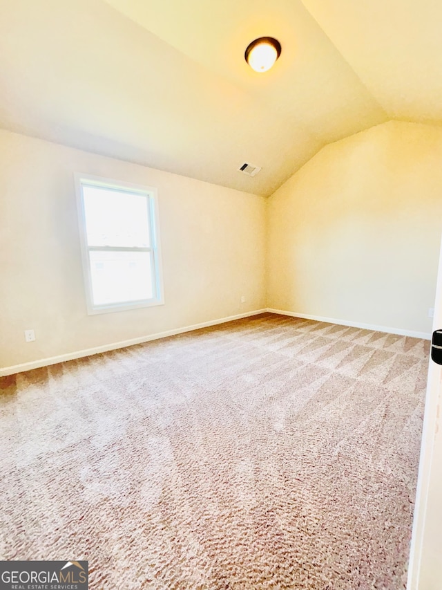 carpeted spare room with lofted ceiling