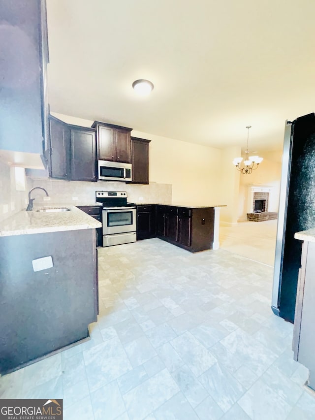 kitchen with decorative backsplash, stainless steel appliances, sink, a fireplace, and decorative light fixtures