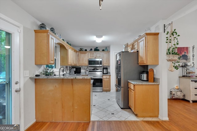 kitchen featuring light hardwood / wood-style flooring, appliances with stainless steel finishes, light stone countertops, light brown cabinets, and kitchen peninsula