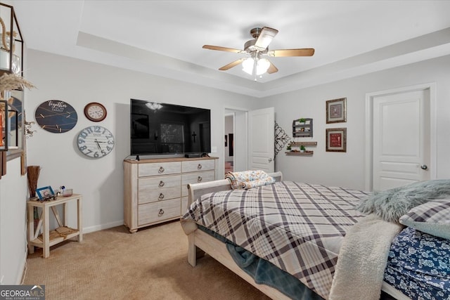 carpeted bedroom featuring ceiling fan and a tray ceiling